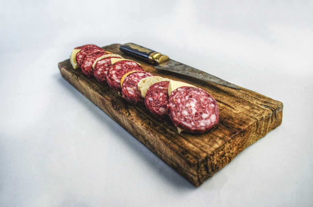 A rustic wooden board displaying sliced salami and a knife, perfect for gourmet presentations.